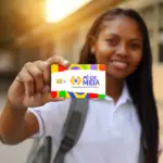 Jovem estudante sorrindo e exibindo o cartão do Pé-de-Meia, programa que pode liberar parcelas de R$ 200 e R$ 1.000 de 2025 nas próximas janelas de pagamento